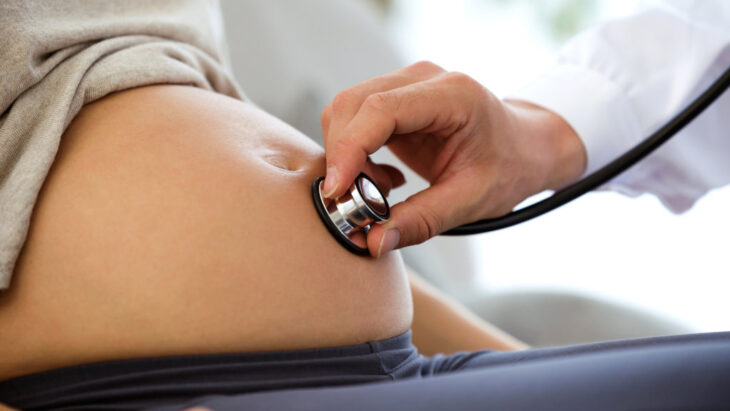 A doctor uses a stethoscope on a pregnant woman