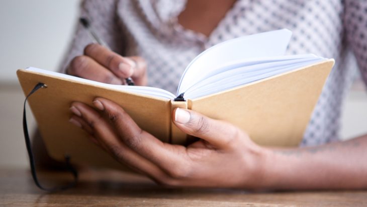 a person writing down in a journal