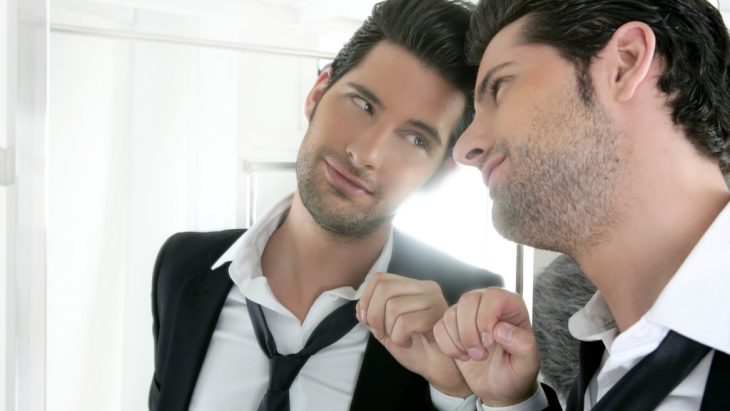 A man confidently smiles to himself in the mirror
