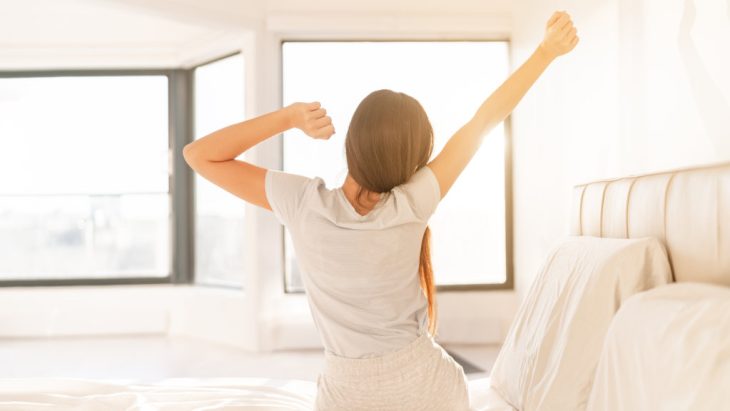 A person stretching in bed after a good night's sleep