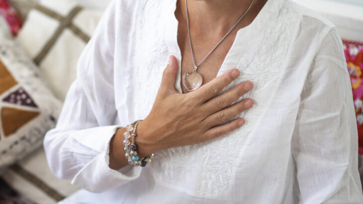 A woman lies a hand on her chest, feeling grateful