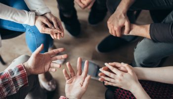 People hold hands at an Alcoholics Anonymous meeting