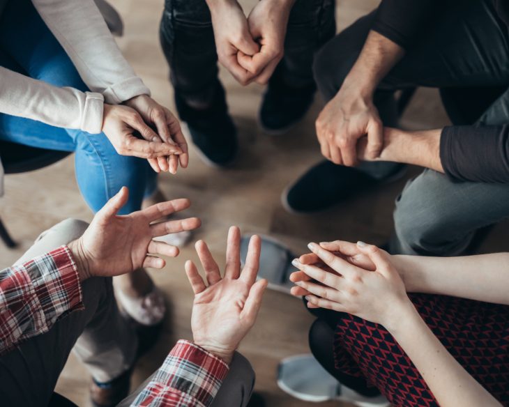 People hold hands at an Alcoholics Anonymous meeting
