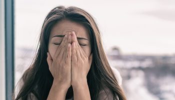 An anxious woman grips her face in a stressful fashion