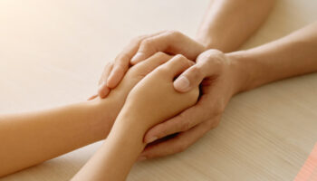 A couple holds hands, supporting each other through a struggle