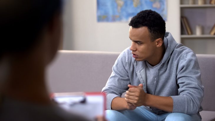 A depressed looking man looks away during a meeting with a doctor