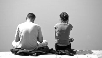 A view of a married couple from behind, in greyscale to communicate a sad or uneasy tone.