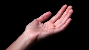 A person reaches out their hand against a black background