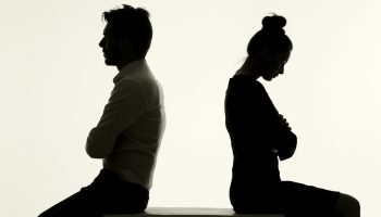 Two people face away from each other against a white background