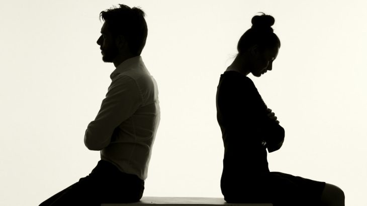 Two people face away from each other against a white background