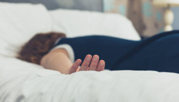 A person lying face-down, passed out on a bed