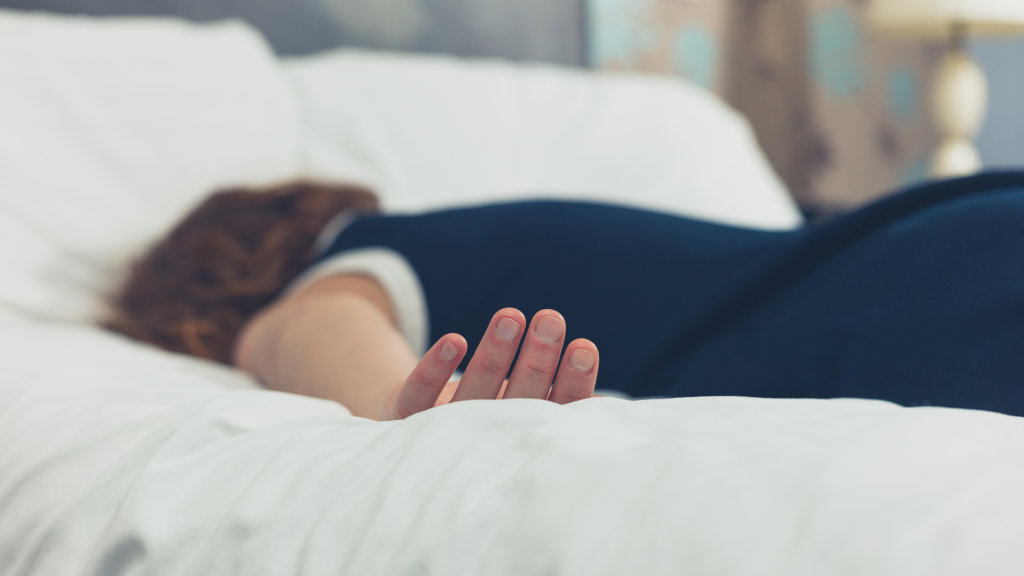 A person lying face-down, passed out on a bed