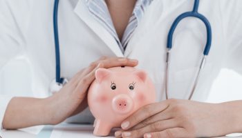 A doctor sitting with a piggy bank in their hands