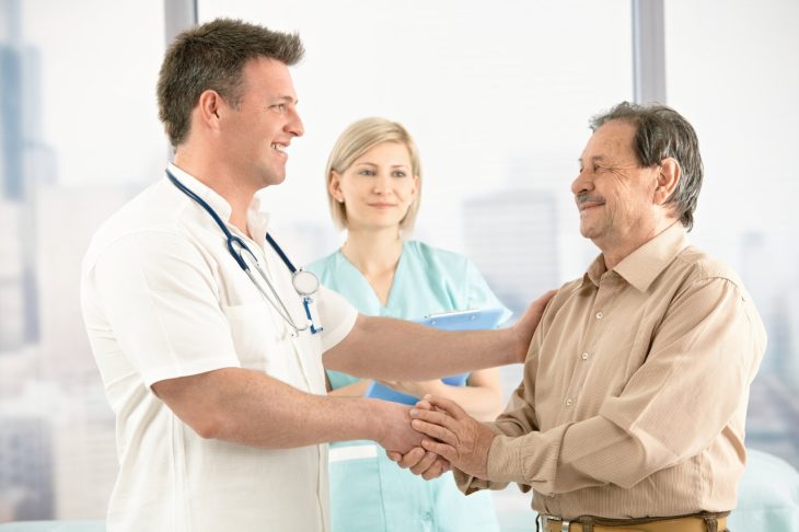 A doctor shakes hands with a patient during a consultation