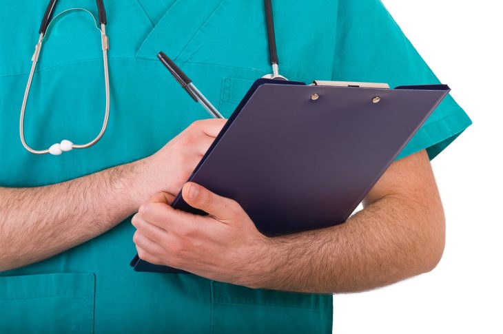A doctor writes something down on a clipboard