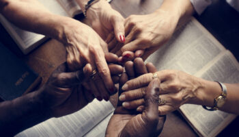 People hold hands over bibles at a Christian detox center