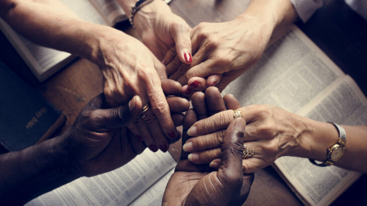 People hold hands over bibles at a Christian detox center