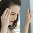 A woman clutches her head as she suffers from a headache, a common symptom of drug withdrawal and detox