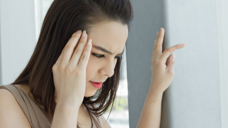 A woman clutches her head as she suffers from a headache, a common symptom of drug withdrawal and detox