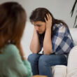 A patient in duress speaks with a doctor during her appointment