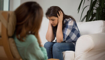 A patient in duress speaks with a doctor during her appointment
