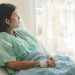 A woman in an inpatient setting sits in a hospital bed