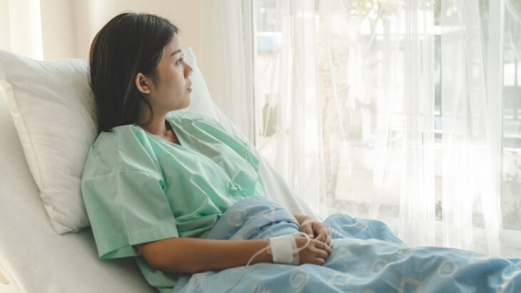 A woman in an inpatient setting sits in a hospital bed