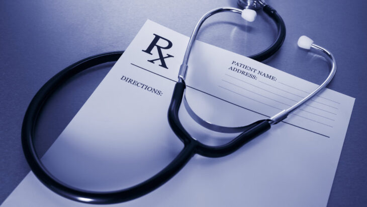 an Rx prescription sheet with a stethoscope sitting on top of it