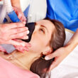 A woman lies in a hospital bed while a doctor places a breathing mask on her face to administer anesthesia, part of a rapid opiate detox regimen