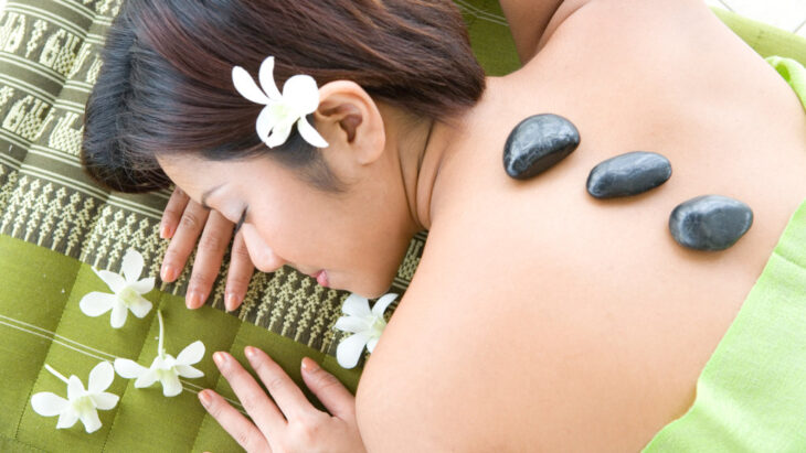 A woman undergoing hot stone therapy, a common feature at luxury and holistic rehab centers