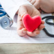 A doctor holding a plus heart, symbolizing recovery and good health