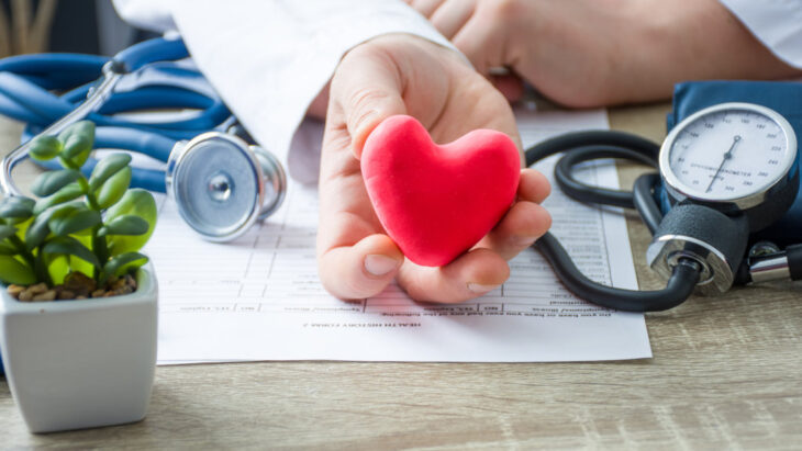 A doctor holding a plus heart, symbolizing recovery and good health