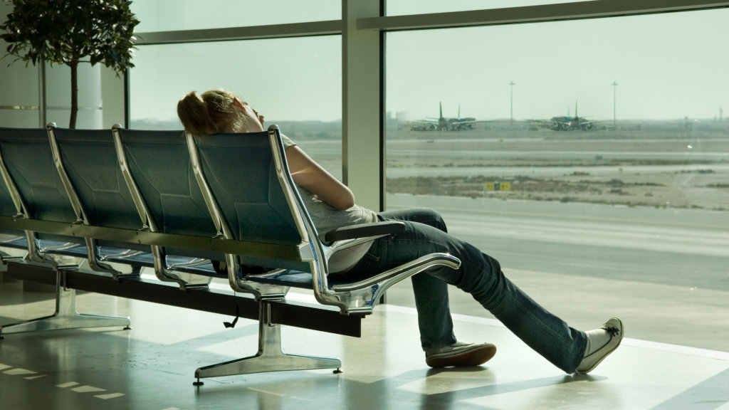 An exhausted woman sits alone in an airport