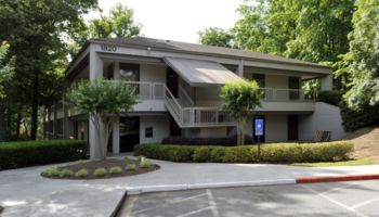 Exterior view of two-story treatment facility with entrance, landscaping, and parking area visible