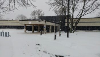 Exterior view of treatment center building with snow coverage, numbered entrance, bare trees, and parking area