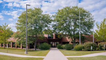 Exterior view of brick treatment facility with manicured lawns, mature trees, and welcoming front entrance walkway