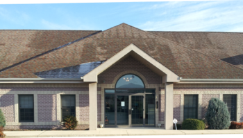 Exterior view of brick treatment facility with main entrance, arched doorway, windows, and landscaping