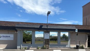 Exterior view of treatment facility with large windows, parking lot, and surrounding landscape under clear sky