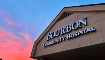 Exterior signage for Bourbon Community Hospital illuminated at dusk with colorful sky background