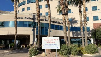 Exterior entrance area with patient and visitor directional signage, palm trees, and covered entrance portico