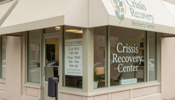 Exterior front entrance of Crisis Recovery Center showing storefront with large windows, awning, and clear facility signage