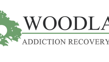Interior facility logo featuring green fleur-de-lis design with Woodlake Addiction Recovery Center text on white background