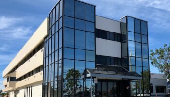Exterior corner view of medical facility showing glass windows, multi-story structure, and entrance area