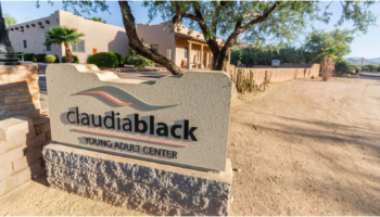 Exterior view of Claudia Black Young Adult Center entrance sign with building and landscaping visible in background