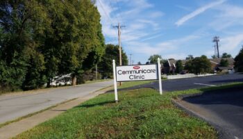 Exterior view of Communicare Clinic entrance sign with facility building and landscaped grounds visible in background