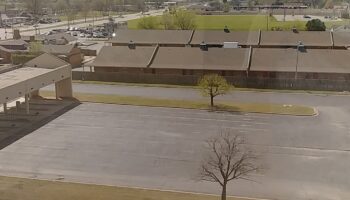 Exterior view of facility building with parking area, landscaped grounds, and surrounding area from elevated perspective