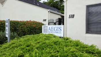 Exterior view of treatment center front entrance with Aegis Treatment Centers LLC sign, landscaping, and building facade