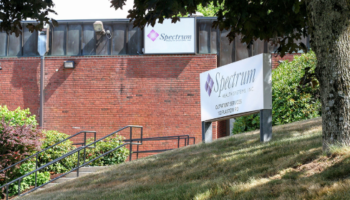 Exterior view of brick building with Spectrum Health Systems signage, landscaped grounds, and metal ramp entrance