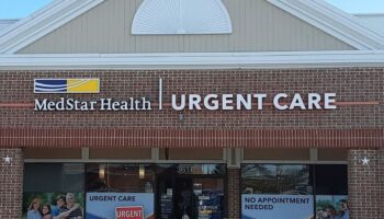 Exterior front facade with MedStar Health Urgent Care signage, brick construction, and entrance doors with promotional window displays