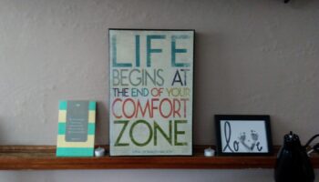 Interior shelf with motivational signage reading 'Life Begins at the End of Your Comfort Zone' and decorative items
